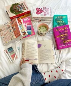 a person laying on top of a bed next to books