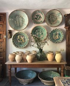 a table topped with bowls and vases next to a wall mounted on the wall