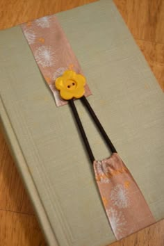 an open book with a yellow flower on the cover and two black handled spatulas sticking out of it