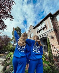 two women in matching blue sweat suits are standing in front of a house