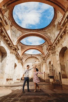 a man and woman are dancing in an old building with skylights above their heads