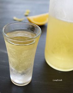 two glasses filled with liquid sitting on top of a table next to lemon wedges