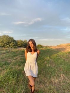 a woman standing in the middle of a field with her hand on her hip and looking at the camera