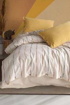 a bed with yellow and white pillows on top of it in front of a colorful wall