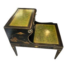 an old black and gold painted desk with two drawers on one side, the other is open