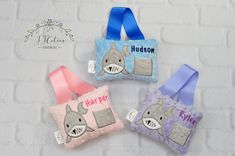 three little purses with name tags on them sitting next to each other in front of a white brick wall