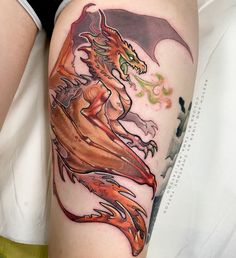 a woman's thigh with a dragon tattoo on her leg and an orange flame coming out of it