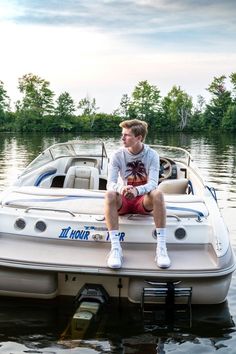 a man sitting on top of a white boat in the middle of a body of water