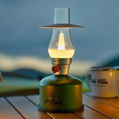 a lamp that is sitting on top of a wooden table next to two mugs