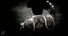 the back of a man in a black and white outfit with a hat on his head