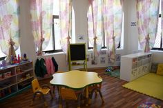 a child's playroom with wooden floors and colorful drapes on the windows