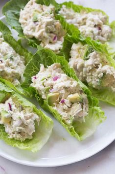 several lettuce wraps with chicken salad on them sitting on a white platter