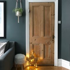 a living room with christmas lights on the floor and a wooden door in front of it