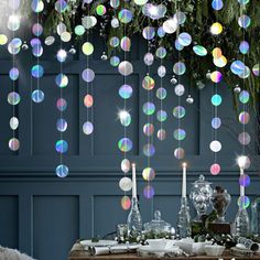 a table topped with lots of bubbles hanging from it's ceiling next to a vase filled with flowers and candles