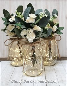 three mason jar vases with white flowers and greenery