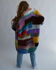 a woman wearing a multicolored knitted ponchle with her back to the camera