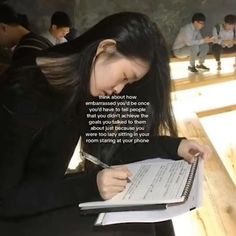 a woman sitting at a desk writing on a piece of paper with the caption