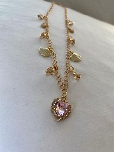 This gold charm necklace features a pink crystal heart charm in the center with shell and crystal charms on the sides. Shell Charm Necklace, Gold Charm Necklace, Crystal Charm, Crystal Heart, Pink Crystal, Gold Charm, Pink Heart, Heart Charm, Austria