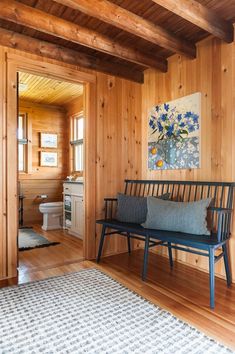 a wooden room with a bench and rug