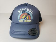 Elevate your beach look with this Rip Curl Sunny Paradise Trucker Hat. The solid blue color complements any outfit, while the mesh back keeps you cool during hot summer days. This one-size-fits-all hat features a vintage-inspired "RIP CURL" brand logo and is perfect for casual occasions. Ideal for men, this hat is a must-have accessory for any beach lover. It's handmade with high-quality materials and includes features such as a mesh back and a comfortable fit. Whether you're heading out for a surf session or just lounging on the beach, this Rip Curl hat is the perfect addition to your outfit. Summer Mesh Trucker Hat With Curved Brim, Blue Baseball Cap For Beach Season, Summer Mesh Trucker Hat With Curved Bill, Curved Bill Hats For Beach In Summer, Summer Mesh Trucker Hat For Outdoor, Blue Trucker Hat For Summer Outdoor Activities, Blue Trucker Hat For Summer Outdoor, Curved Bill Beach Hat For Summer, Summer Sports Hat With Mesh Back