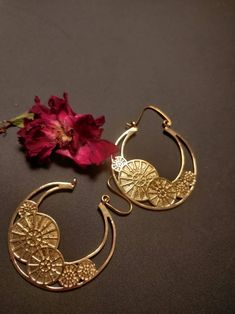 "Transform your look into an eye-catching masterpiece with our Sunwheel Earrings. Handmade with love and crafted from 100% brass, these Gold toned earrings feature a striking Mandala pattern with an edgy Megatron inspired design and intricate hook detailing. Perfect for any occasion, whether it's a yoga session, boho festival, or your special day as a boho bride, these earrings are versatile enough to complement any style. Channel your inner goddess and radiate positive energy with these tribal danglers that also serve as healing jewelry. Elevate your jewelry collection with these must-have Sunwheel Earrings. Order now and experience the beauty and power of handmade boho adornments." Vintage Brass Danglers, Gold Teardrop Earrings With Artistic Design, Vintage Brass Chandbali Earrings, Festive Vintage Brass Earrings, Handmade Metal Fusion Danglers, Bohemian Metal Hoop Earrings For Wedding, Bohemian Bronze Earrings With Intricate Design, Brass Earrings With Unique Design For Gift, Bohemian Hoop Earrings With Intricate Design For Wedding