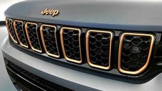 the front grille of a jeep with gold grills on it's headlamps