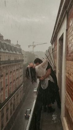 two people standing on top of a building in the rain