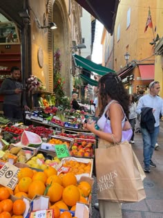 people shopping at an outdoor market with oranges and other fruits