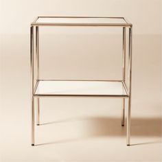 a glass and metal side table against a beige background