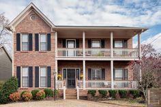 a two story brick house with black shutters and balconies on the second floor