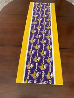 a purple and yellow table runner sitting on top of a wooden table