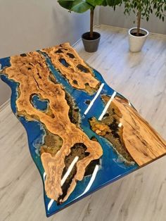 a table that is made out of wood and blue paint on the top, with a plant in the background