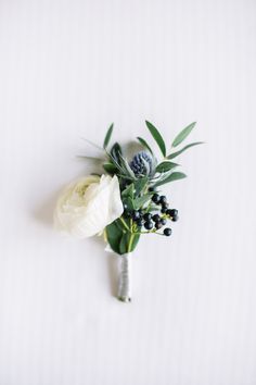 a boutonniere with flowers and greenery on a white background, top view