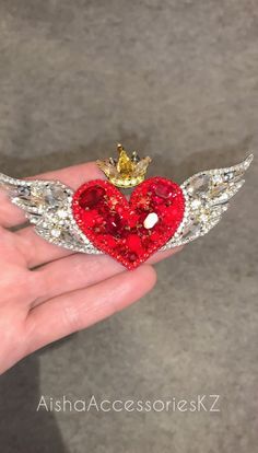 someone is holding a heart with wings and a crown