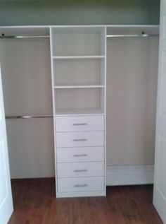 an empty closet is shown with white drawers and shelves on the wall, along with wooden flooring