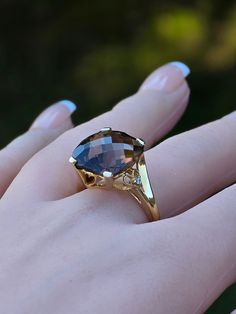 a woman's hand with a ring on it that has a large blue stone in the middle