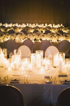 the tables are set with white flowers and lit candles for an elegant dinner or reception