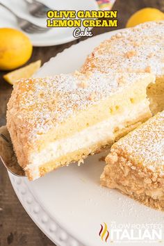 a white plate topped with a cake covered in powdered sugar next to lemons