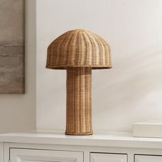 a wicker lamp sitting on top of a white cabinet