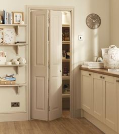 an open door leading into a kitchen with lots of shelves and cupboards in it