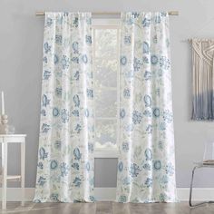 the curtains in this room are made from white and blue floral print, with an open window