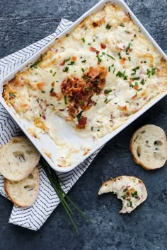 a casserole dish with meat and cheese in it next to slices of bread