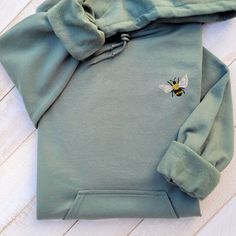 Really soft and comfortable unisex embroidered hoodie with a cute bee embroidered on it made of high quality! Classic fit, 50/50 cotton/polyester. Each hoodie is made in the size and color of your choice, with a unique design. I suggest you use your usual size for a better fit or choose a size for a looser fit.   Hoodies in unisex style with unique design the perfect gift for your best friend, loved one or your new favorite crewneck hooded sweatshirt for autumn, winter, spring and even cool summ Green Hooded Hoodie With Letter Embroidery, Embroidered Fleece Hoodie, Green Hoodie With Letter Embroidery, Green Casual Hoodie With Custom Embroidery, Casual Green Hoodie With Custom Embroidery, Embroidered Fleece Hooded Sweatshirt, Embroidered Cotton Hoodie, Green Hooded Sweatshirt With Custom Embroidery, Green Embroidered Hooded Sweatshirt