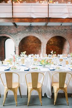 the tables are set with white linens and gold chairs