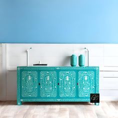 a blue and white sideboard sitting on top of a hard wood floor next to a wall