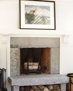 a fireplace with logs stacked on top of it and a framed painting above the fire place