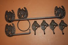 four metal horse head hooks hang on a wall next to two towel racks and one shelf