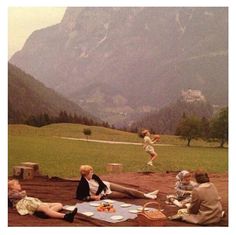 several people sitting on the ground in front of mountains