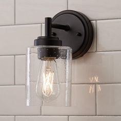 a light that is on the wall next to a white tiled wall in a bathroom