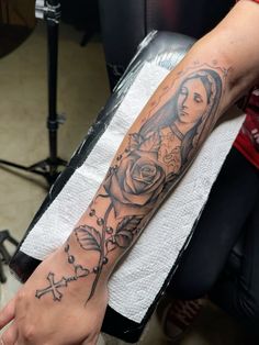 a woman with a rose and cross tattoo on her arm